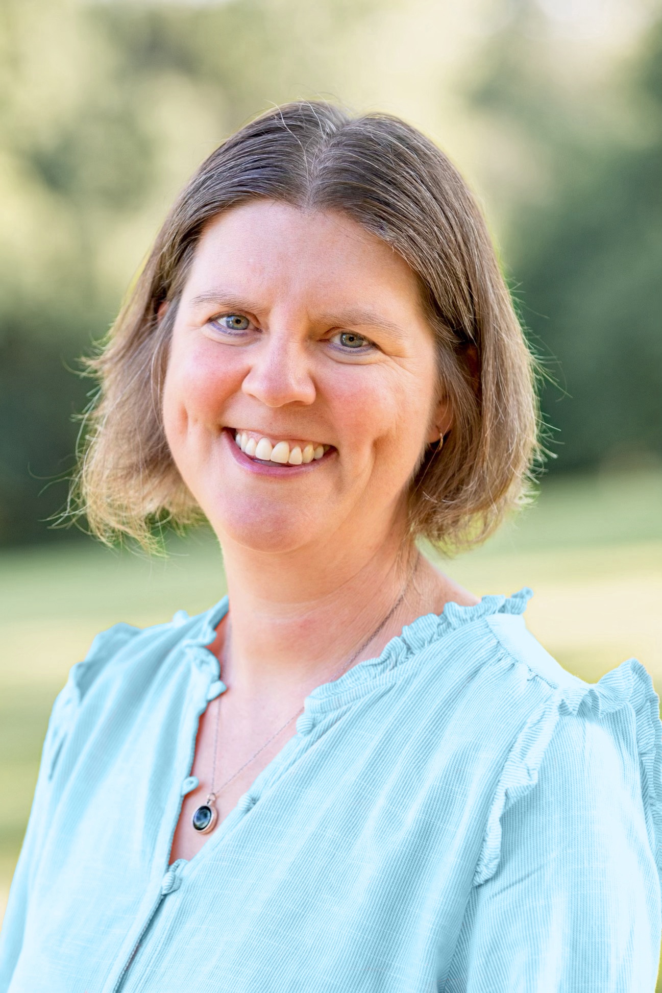 Amy McCrea, GI dietitian, smiling outdoors in a light blue blouse